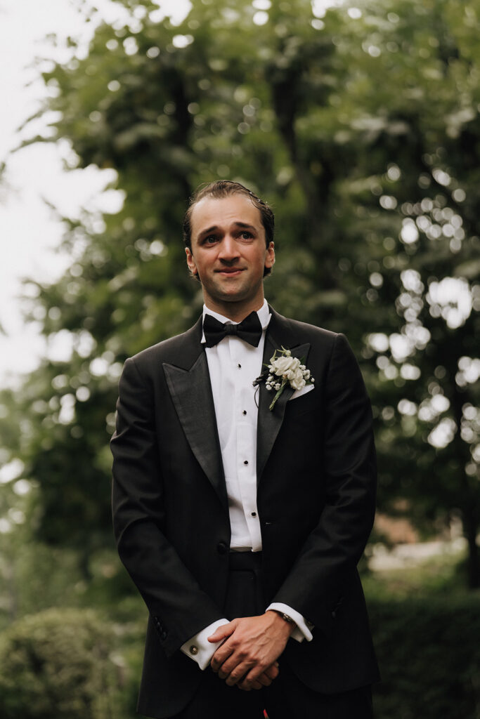 the groom standing at the altar of a wedding ceremony with tears in his eyes as he watches the bride walk down