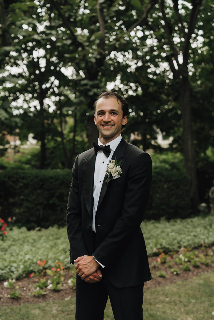 a groom in a black tux smiling on his wedding day